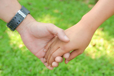 Cropped image of woman holding hands on field