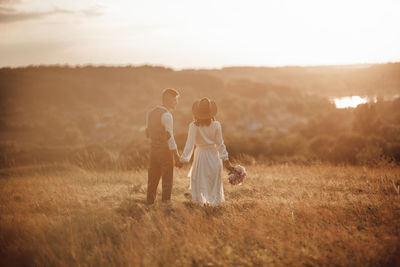 Rear view of couple on field at sunset