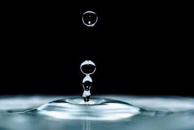 Close-up of drop falling in water against black background