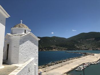 Church by sea against clear blue sky