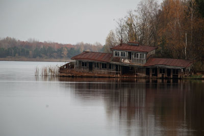 House by lake against sky