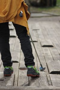 Low section of child playing golf on boardwalk