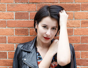 Portrait of a young woman against brick wall