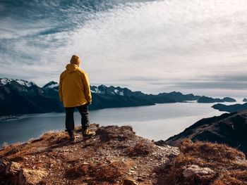 Rear view of man standing on mountain against sky