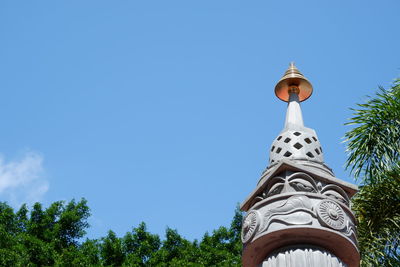 Low angle view of tower amidst trees and building against sky