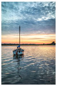 Sailboat in sea against sky during sunset