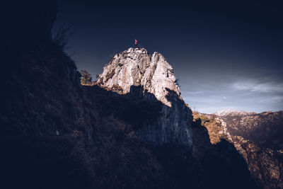Low angle view of person on rock against sky
