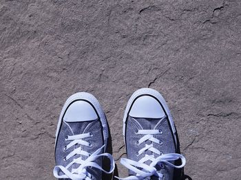 Low section of person wearing canvas shoe while standing on rock