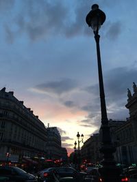 Low angle view of city street against cloudy sky