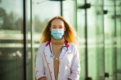 Female doctor standing against wall