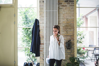 Smiling female entrepreneur talking through smart phone at home office