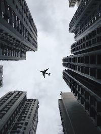 Directly below shot of airplane flying against sky in city