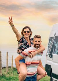 Portrait of smiling friends with arms raised standing on field