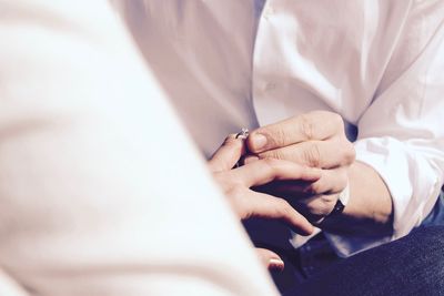 Midsection of man putting engagement ring on girlfriend finger