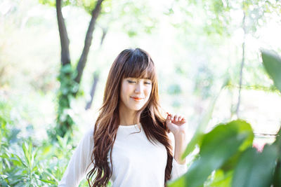 Portrait of smiling young woman standing against trees