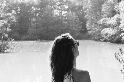 Portrait of woman looking at lake against trees