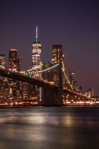 Illuminated modern buildings in city against sky at night