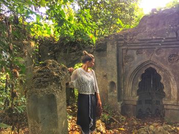 Rear view of woman standing by tree against building