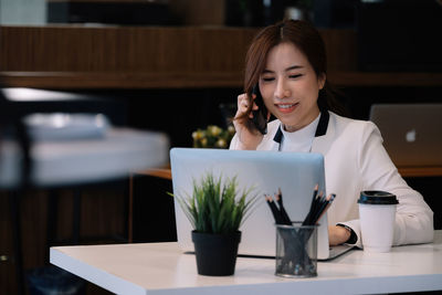 Young woman using smart phone on table