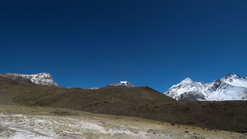 Scenic view of snowcapped mountains against clear blue sky