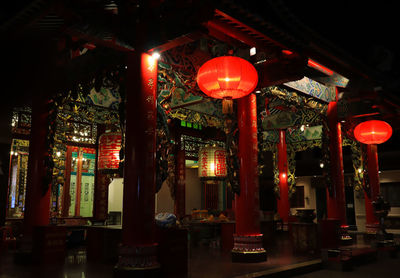 Illuminated lanterns hanging by building at night