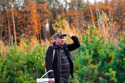 Man in the forest, a hunter, a mushroom picker in a military cap stands in the forest and points way