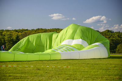 Preparing a green hot air balloon for flight by heating the air with a gas burner.