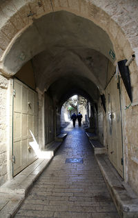 Rear view of people walking on footpath amidst buildings