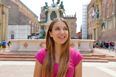 Portrait of smiling woman against building in city