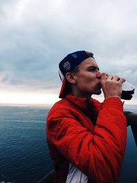 Side view of young man looking away against sky