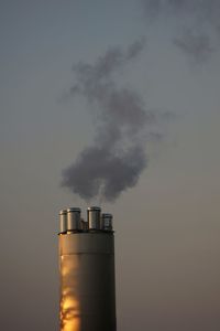 Smoke emitting from chimney against sky