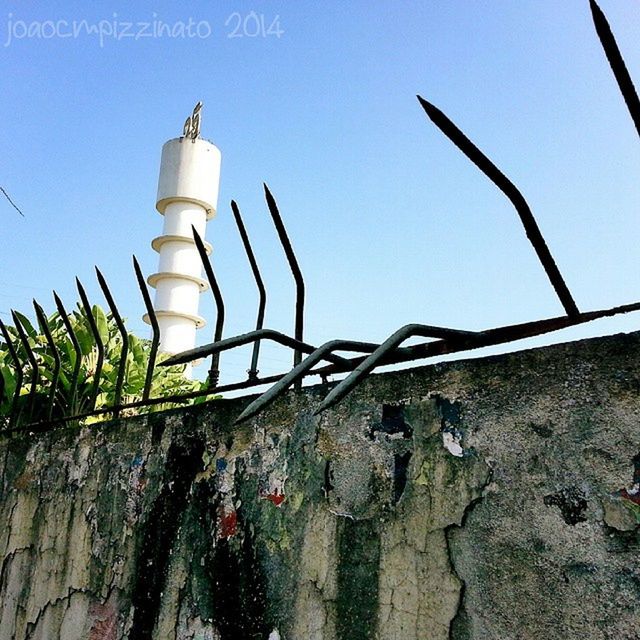 built structure, architecture, building exterior, low angle view, clear sky, wall - building feature, plant, metal, sunlight, day, protection, no people, old, blue, safety, lighting equipment, security, outdoors, close-up, sky