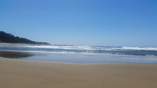 Scenic view of beach against clear blue sky