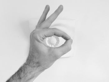 Cropped image of man showing okay sign over artwork on table