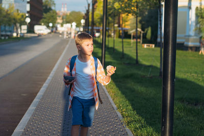 Caucasian boy walking from school wearing school bag. begining of academic year