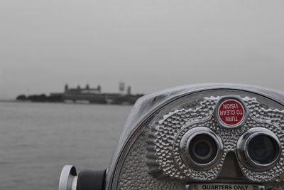 Close-up of coin-operated binoculars against sea