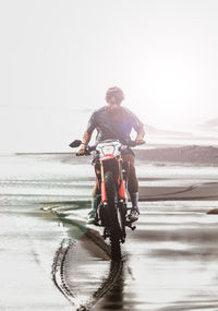 Man riding bicycle on beach against sky