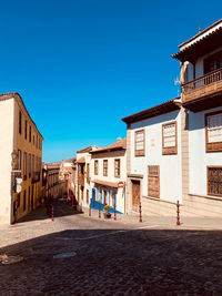 Street amidst buildings against clear blue sky