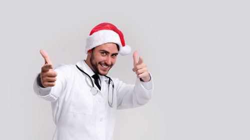 Portrait of smiling young woman standing against white background