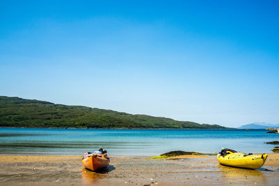 Boat moored on sea against clear blue sky