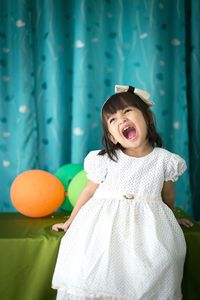 Portrait of smiling girl standing against wall