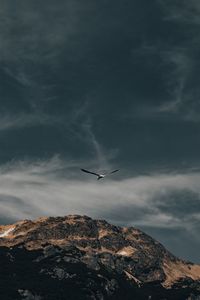 Low angle view of airplane flying over mountain against sky