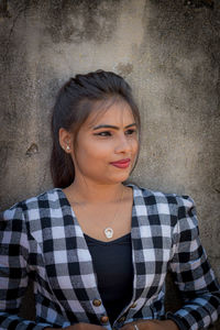 Portrait of young woman standing against wall