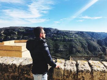 Young man standing on mountain against sky