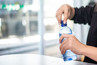 Close-up of hand holding bottle against blurred background