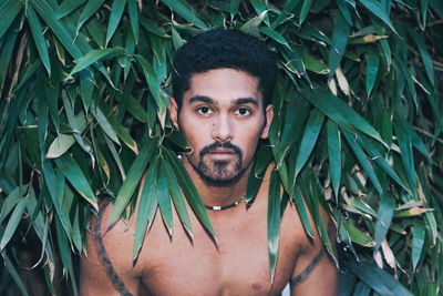 Portrait of shirtless young man amidst leaves
