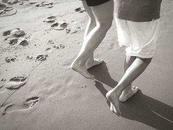 Low section of couple walking at beach