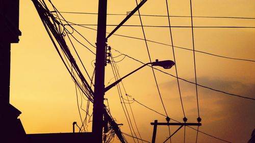 Low angle view of silhouette electricity pylon against sky