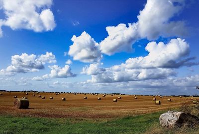 Hay bales on field against sky