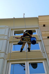 Low angle view of man working against clear sky